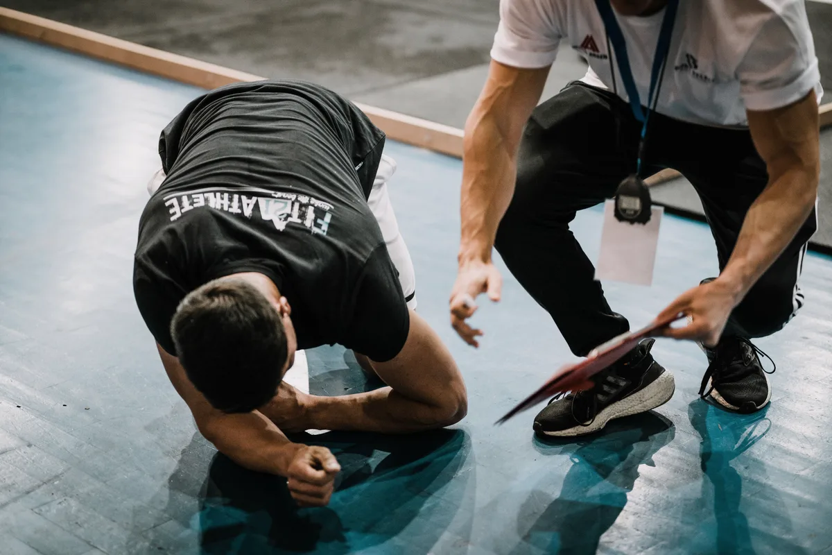 A trainer guiding a beginner through a floor exercise, correcting their position